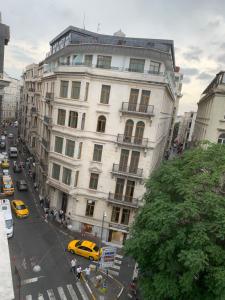 伊斯坦堡的住宿－MyHouseBosphorus，一条城市街道上的白色大建筑,有黄色的出租车
