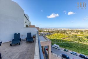 uma varanda com duas cadeiras e uma mesa num edifício em Beautiful PENT with terrace & spectacular views by 360 Estates em Luqa