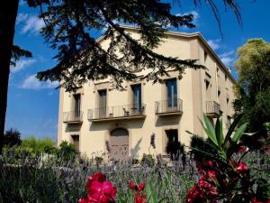 Winery apartment for two with private terrace في La Torre de Claramunt: مبنى أمامه زهور