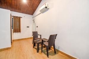 Zimmer mit 2 Stühlen, einem Tisch und einem Ventilator in der Unterkunft FabExpress Peacock Suites in Goa