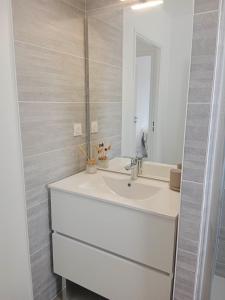 ein weißes Badezimmer mit einem Waschbecken und einem Spiegel in der Unterkunft APPARTEMENT 4 COUCHAGES in Soustons