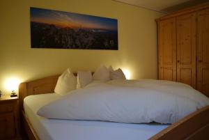 1 dormitorio con 1 cama blanca y una pintura en la pared en Schererhof, en Rimsting