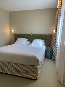 a bedroom with a large bed with white sheets and pillows at Hotel des Victoires - Restaurant in Cannes