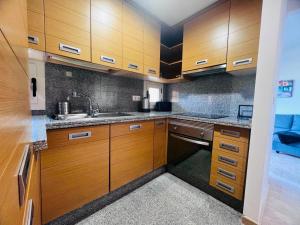 Una cocina con gabinetes de madera y un fregadero. en Sol Andalusi, en Alhaurín de la Torre