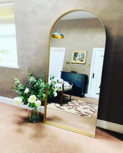 a mirror in a room with a vase of flowers at The Bothy in Kelso