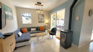 Una sala de estar con un sofá y una estufa. en VILLA CASA KOKO 10 PERS piscine chauffée, pétanque, ping pong VIEUX-BOUCAU, en Vieux-Boucau-les-Bains