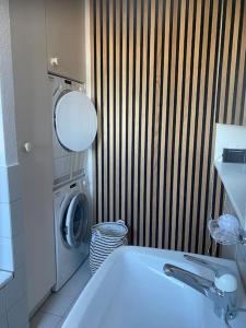 y baño con lavadora y lavabo blanco. en 2 1/2-Zi-Wohnung (Bijou im Stadtzentrum), en Murten