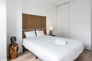 a bedroom with a large white bed and a brick wall at GuestReady - Mystic Subdual in Porto