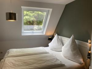 Schlafzimmer mit einem Bett mit weißer Bettwäsche und einem Fenster in der Unterkunft Ferienwohnung Kurparkhaus 19c Wyk in Wyk auf Föhr