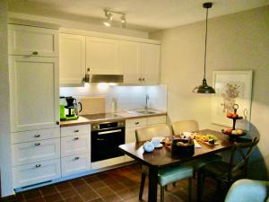 eine Küche mit weißen Schränken und einem kleinen Tisch mit Stühlen in der Unterkunft Ferienwohnung Kurparkhaus 19c Wyk in Wyk auf Föhr