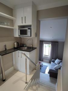 a small kitchen and living room with a couch at Hilltop Guesthouse in Bellville
