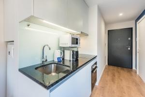 a kitchen with a sink and a microwave at GuestReady - Theater Apartment in Porto