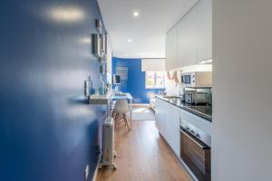 a kitchen with white cabinets and a blue wall at GuestReady - Theater Apartment in Porto