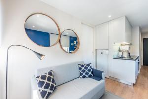 a living room with a blue couch and two mirrors at GuestReady - Theater Apartment in Porto