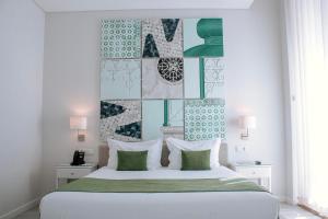 um quarto com uma cama branca com almofadas verdes e brancas em Rio Art Hotel em Setúbal
