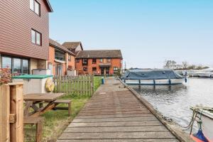 a dock with a boat on the water next to a house at Kingsmere in Horning