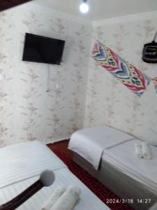 a hotel room with two beds and a tv at Nur-Niso Guest House in Bukhara