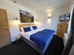 ein Hotelzimmer mit einem Bett mit blauer und weißer Bettwäsche in der Unterkunft Pension Jitřenka Hřensko in Hřensko
