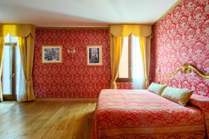 ヴェネツィアにあるレシデンツァ カ サン マルコの赤い壁紙とベッド、窓が備わるベッドルーム1室が備わります。