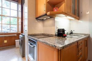 - une cuisine avec des placards en bois et des comptoirs en granit dans l'établissement GuestReady - City Blossom, à Porto