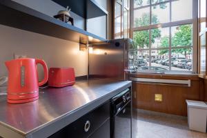 une cuisine avec des appareils rouges sur un comptoir avec une fenêtre dans l'établissement GuestReady - City Blossom, à Porto
