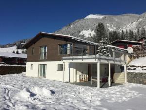 uma casa na neve em frente a uma montanha em Ferienwohnung Saturn - b48834 em Sörenberg