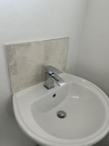 ein weißes Waschbecken mit einem silbernen Wasserhahn in der Unterkunft 3 Bed House with free parking in Wolverhampton
