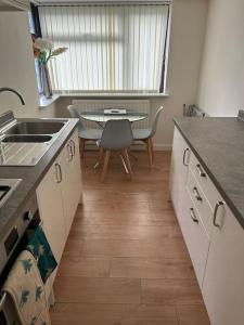 a kitchen with a sink and a table with chairs at 3 Bed House with free parking in Wolverhampton