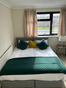 a bedroom with a large bed with green and yellow pillows at 3 Bed House with free parking in Wolverhampton