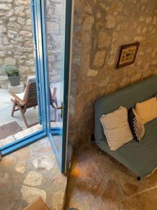 eine grüne Couch mit Kissen neben einer Steinmauer in der Unterkunft Art stone house Belle in Tribunj
