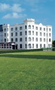 a white building with a grass field in front of it at Upstalsboom Borkum in Borkum