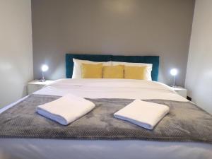 un grande letto con due asciugamani bianchi sopra di Hazelhurst House - 4 bedrooms 2 bathrooms a Stoke on Trent
