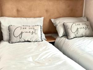 two beds with white sheets and a pillow that says be our guest at Impeccable 2-Bed Lodge in Preston hot hub in Preston