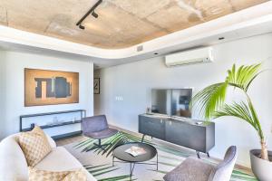 a living room with a couch and chairs and a tv at The Quarter Apartments in Cape Town