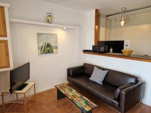 a living room with a leather couch and a tv at Apartamentos Wundermar in Torredembarra