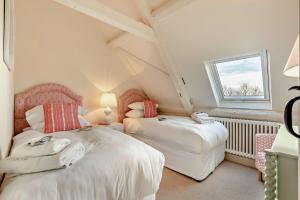 two beds in a attic room with a window at Owl Barn in Aston