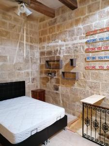 - une chambre avec un lit et un mur en briques dans l'établissement Old refurbished Apartment in Bormla, à Cospicua