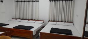 two beds in a small room with curtains at Sahasna Holiday Home in Diyatalawa