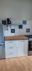 une cuisine avec des placards blancs et un comptoir en bois dans l'établissement Bienvenue chez vous, au Puy-en-Velay