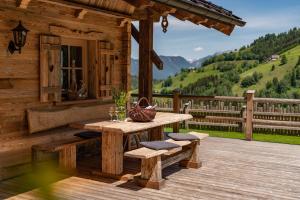 eine Holzterrasse mit einem Tisch und Bänken auf einer Hütte in der Unterkunft Almchalet zu Pruggern bey FeWo-PLAN in Pruggern