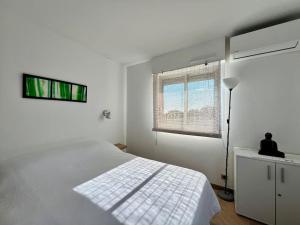 ein weißes Schlafzimmer mit einem Bett und einem Fenster in der Unterkunft Fidji, appartement vue mer panoramique in La Ciotat