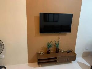 a living room with a television on a wall with a table at Brenthill Condo (Ceramic Unit) in Baguio