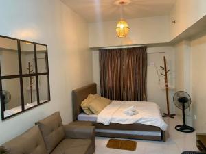 a small bedroom with a bed and a couch at Brenthill Condo (Ceramic Unit) in Baguio