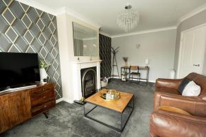un soggiorno con divano e TV di WOODFIELD ROAD - Two bed in Harrogate with cosy living room fire. a Harrogate