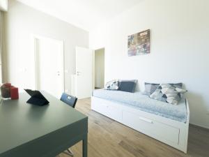 a white bedroom with a bed and a table at Realkasa Creti Apartment in Bologna