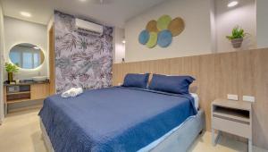 um quarto com uma cama azul e um espelho em Miami Hotel Cartagena - Luxury Apartments em Cartagena das Índias