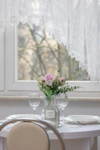a table with a vase of flowers and two glasses at Comfortable Apartment with Balcony in Krakow by Rent like home in Krakow