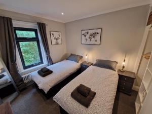 two beds in a room with a window at Newly renovated 2-bed bungalow in Bath