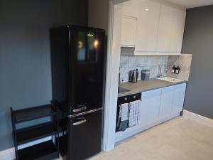 a black refrigerator in a kitchen with white cabinets at Newly renovated 2-bed bungalow in Bath