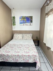 um quarto com uma cama com colcha floral em RJ Residencial Nosso Sonho com Piscina a 120m mar em Palhoça